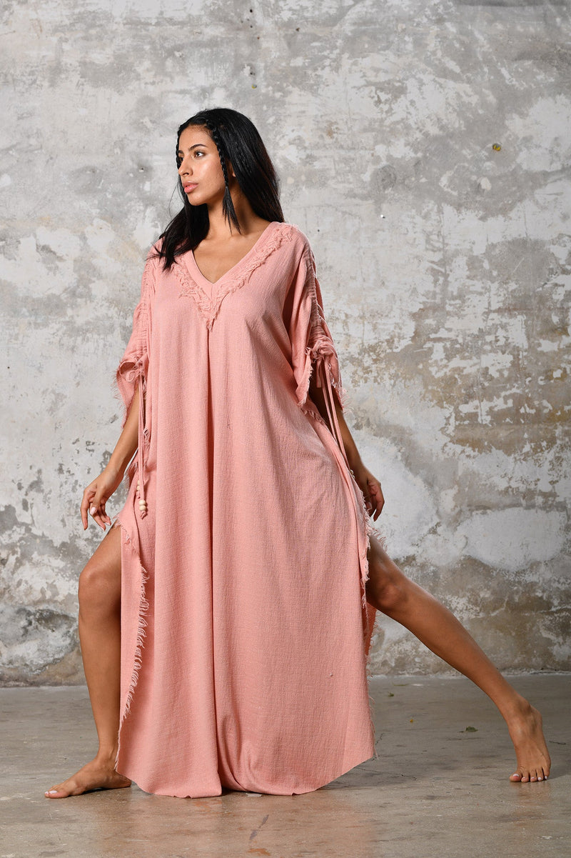 A versatile, pink earthy goddess dress that embodies boho-chic style. Crafted from the softest cotton fabric, this garment offers both comfort and a fashion statement. The dress can be worn in two distinct styles, either as a kaftan or a sultry dress, with a simple change in the way you put it on. Its natural and ethereal design exudes a warm, comforting feeling against your skin, making it a must-have addition to your wardrobe for those seeking a harmonious blend of style and comfort.