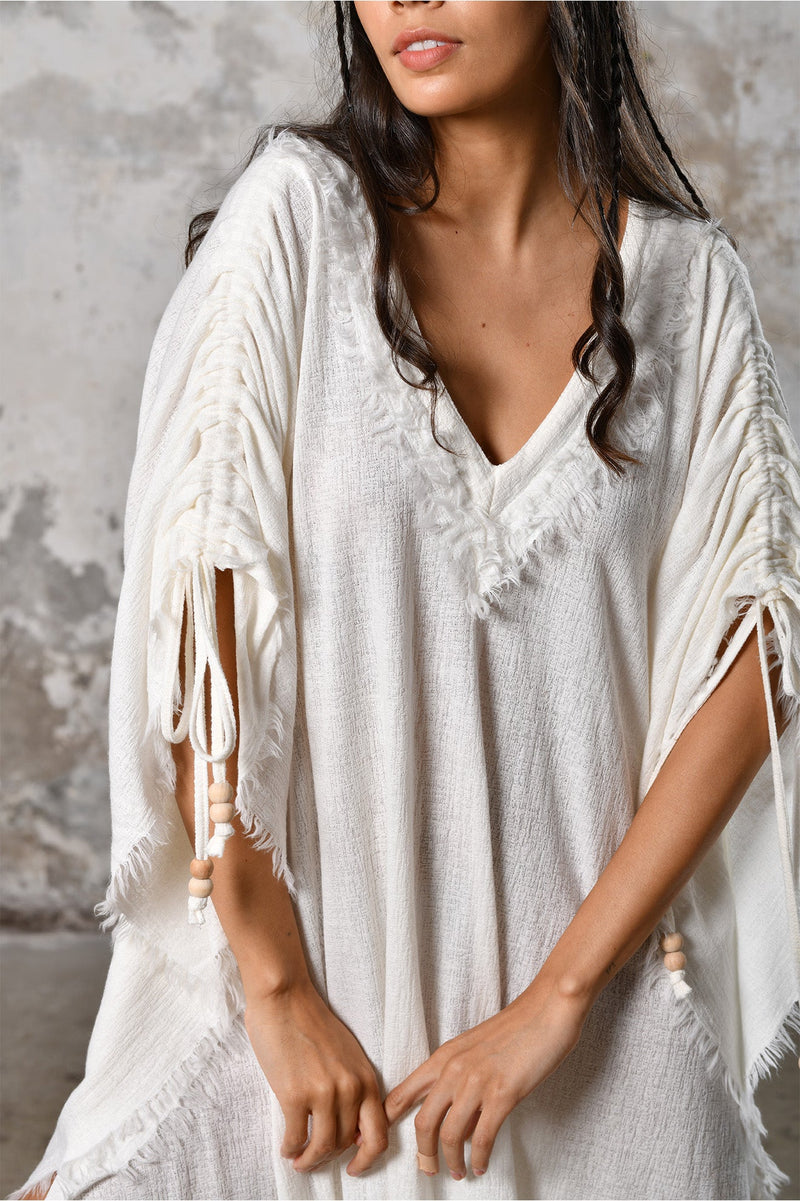 A versatile, White earthy goddess dress that embodies boho-chic style. Crafted from the softest cotton fabric, this garment offers both comfort and a fashion statement. The dress can be worn in two distinct styles, either as a kaftan or a sultry dress, with a simple change in the way you put it on. Its natural and ethereal design exudes a warm, comforting feeling against your skin, making it a must-have addition to your wardrobe for those seeking a harmonious blend of style and comfort.